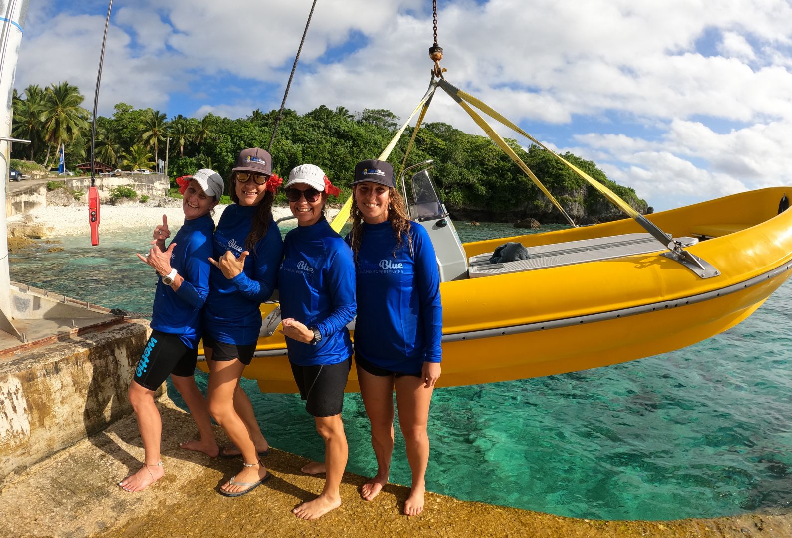 a group of people posing for a photo next to a yellow boat