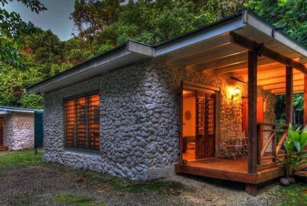 a house with a stone wall and a wood roof