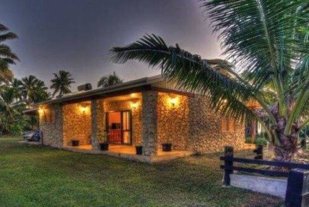 a house with palm trees and a bench in front of it