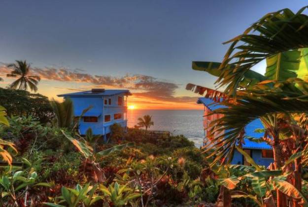 a house on a hill by the water during sunrise