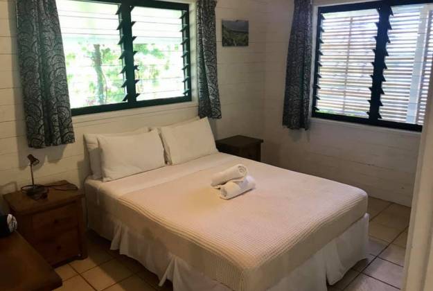 A bed with white sheets inside the namukula cottage
