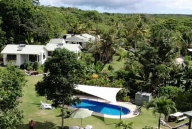 A group of houses with trees and a swimming pool at accommodation Namukulu Cottages